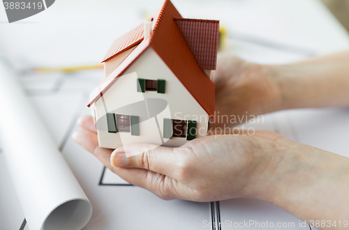 Image of close up of hands with house model above blueprint