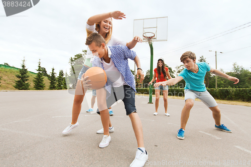 Image of group of happy teenagers playing basketball