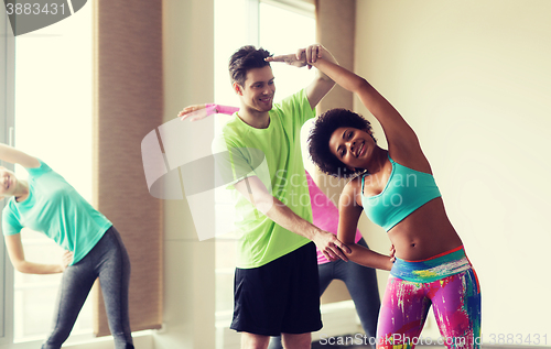 Image of group of smiling people stretching in gym