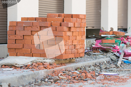 Image of New bricks are stacked on a pallet stand at the trade pavilions around construction debris