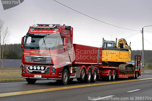 Image of Red Volvo FH16 750 Transports Crawler Excavator in the Evening