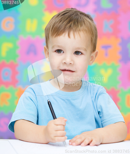 Image of Little boy is writing on his copybook