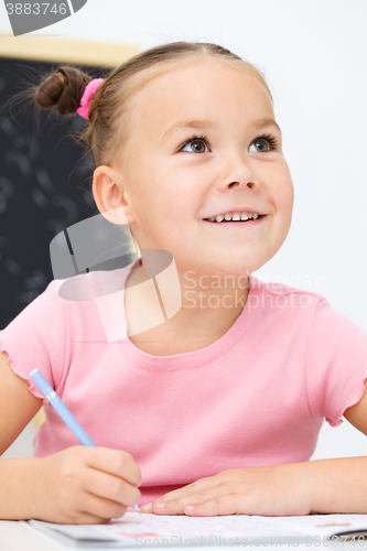 Image of Little girl is writing using a pen