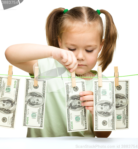 Image of Cute little girl is playing with paper money