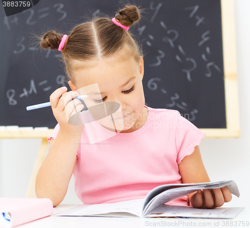 Image of Little girl is writing using a pen