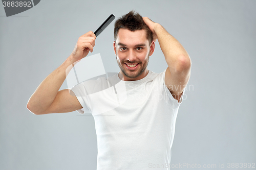 Image of happy man brushing hair with comb over gray