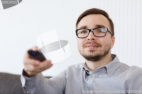 Image of smiling man with tv remote control at home