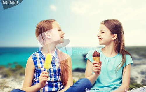 Image of happy little girls eating ice-cream over beach