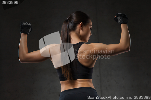 Image of young woman flexing muscles in gym