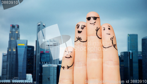 Image of close up of fingers with smiley faces over city