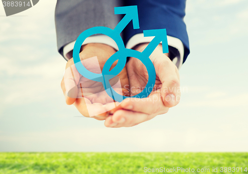 Image of close up of male gay couple holding gender symbol