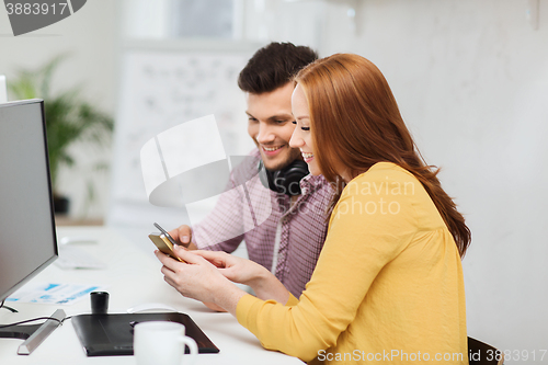Image of smiling creative team with smartphones at office