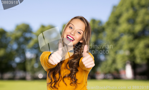 Image of happy young woman or teen girl showing thumbs up