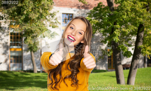 Image of happy young woman or teen girl showing thumbs up