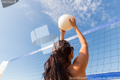 Image of young woman with ball playing volleyball on beach