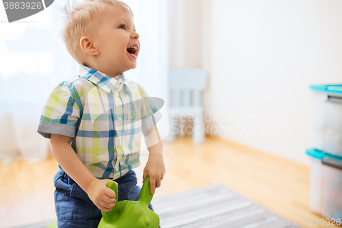 Image of happy baby boy playing with ride-on toy at home