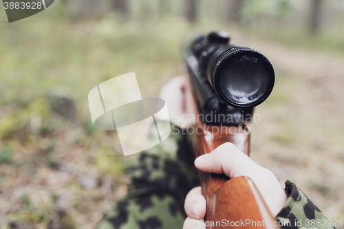 Image of close up of soldier or hunter with gun in forest