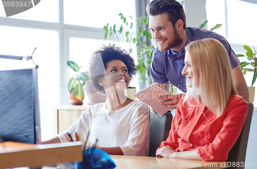 Image of happy creative team with computer in office