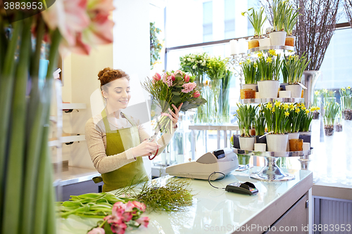 Image of smiling florist woman making bunch at flower shop