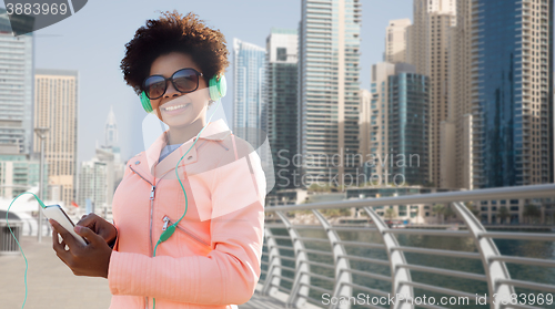 Image of happy young woman with smartphone and headphones