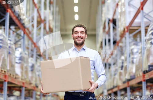 Image of happy man with cardboard parcel box at warehouse