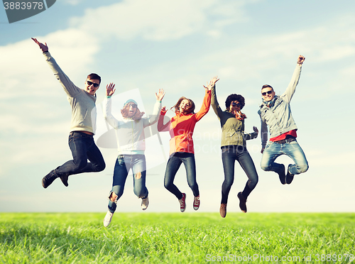 Image of smiling friends in sunglasses jumping high