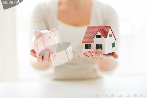 Image of close up of woman with house model and piggy bank