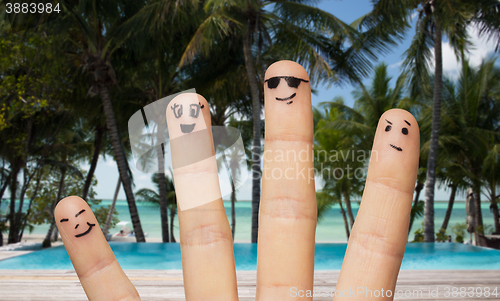 Image of close up of fingers with smiley faces on beach