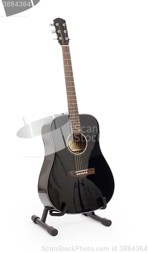 Image of Black acoustic guitar on stand, isolated