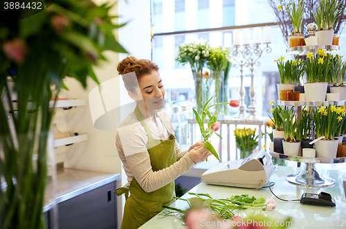 Image of smiling florist woman making bunch at flower shop