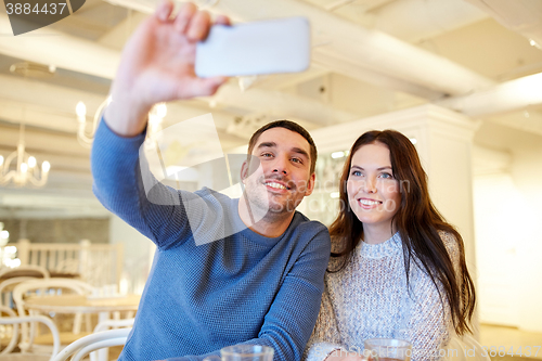 Image of couple taking smartphone selfie at cafe restaurant