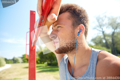 Image of young man with earphones and horizontal bar