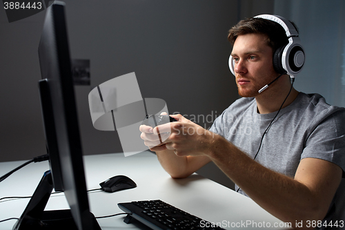 Image of man in headset playing computer video game at home