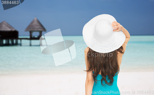 Image of woman in swimsuit and sun hat from back on beach