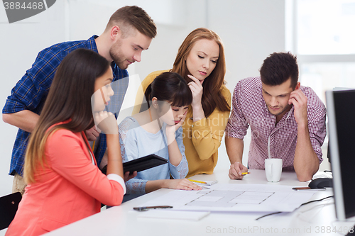 Image of creative team with blueprint working at office