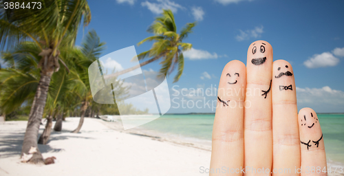 Image of close up of fingers with smiley faces on beach