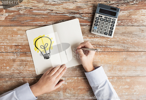 Image of close up of hands with calculator and notebook