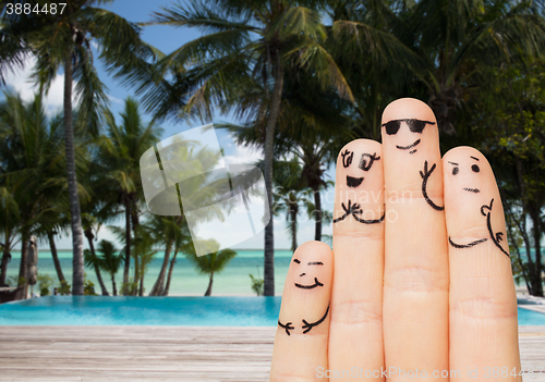 Image of close up of fingers with smiley faces on beach