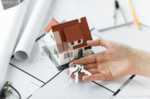 Image of close up of hand with house keys and blueprint