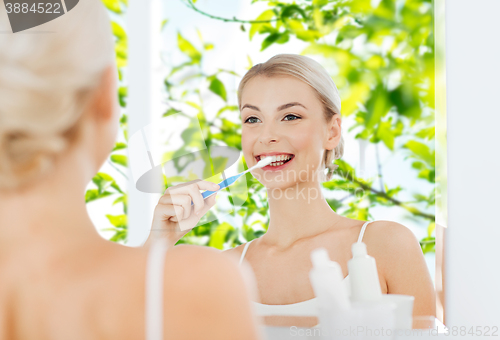 Image of woman with toothbrush cleaning teeth at bathroom