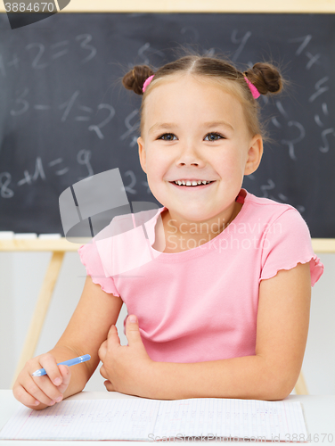 Image of Little girl is writing using a pen