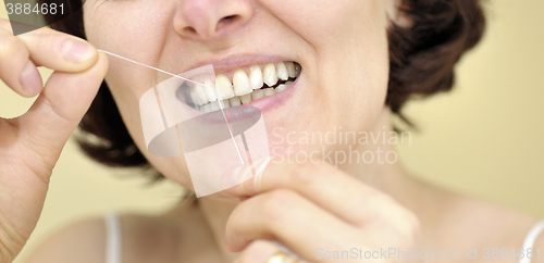 Image of Woman flossing her teeth 