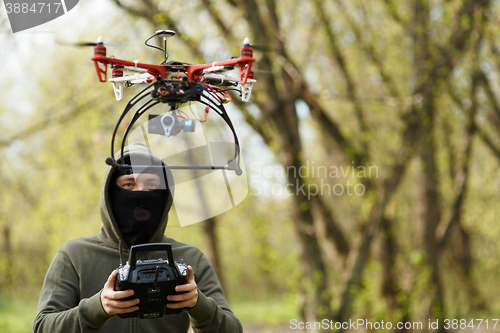 Image of Man in mask operating a drone with remote control.