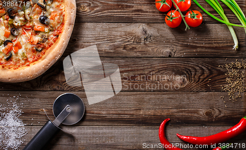 Image of Tasty pizza with ingridients on a wooden board.