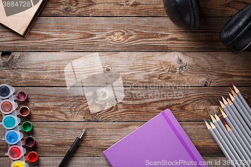 Image of Watercolors, color pencils and sketchbook on wooden table. Flat lay photo with empty space for logo, text.