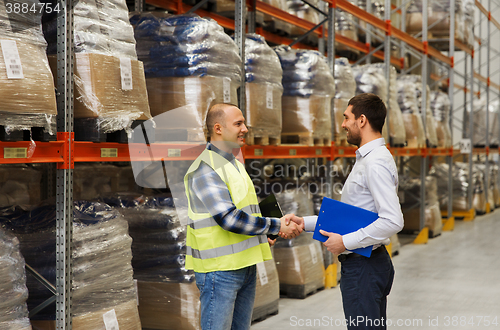 Image of worker and businessmen with clipboard at warehouse