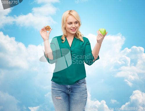 Image of smiling woman choosing between apple and cookie