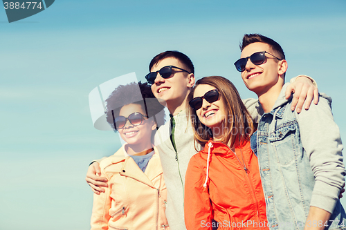 Image of happy teenage friends in shades hugging outdoors