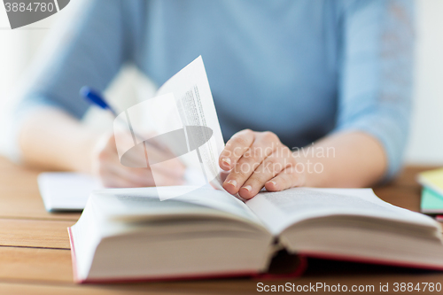 Image of close up of student with book and notebook at home