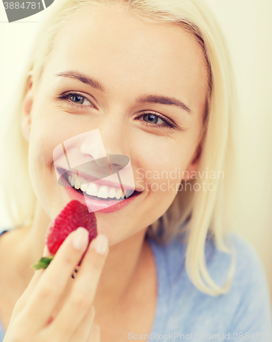 Image of happy woman eating strawberry at home